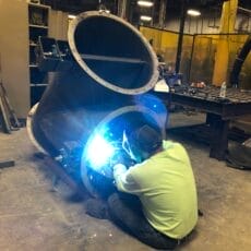 A Kelair shop worker welds together an industrial damper.